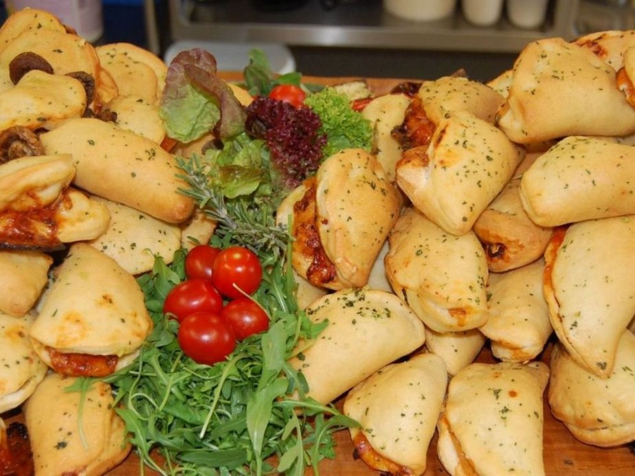 Viele Calzone-Pizzen liegen nebeneinander.